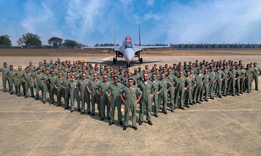 Indian Air Force personnel pose in front of a Rafale fighter jet.