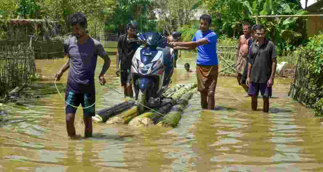 People transport a motorcycle through a flood-affected area on a makeshift raft after heavy rainfall in Golaghat, Assam.