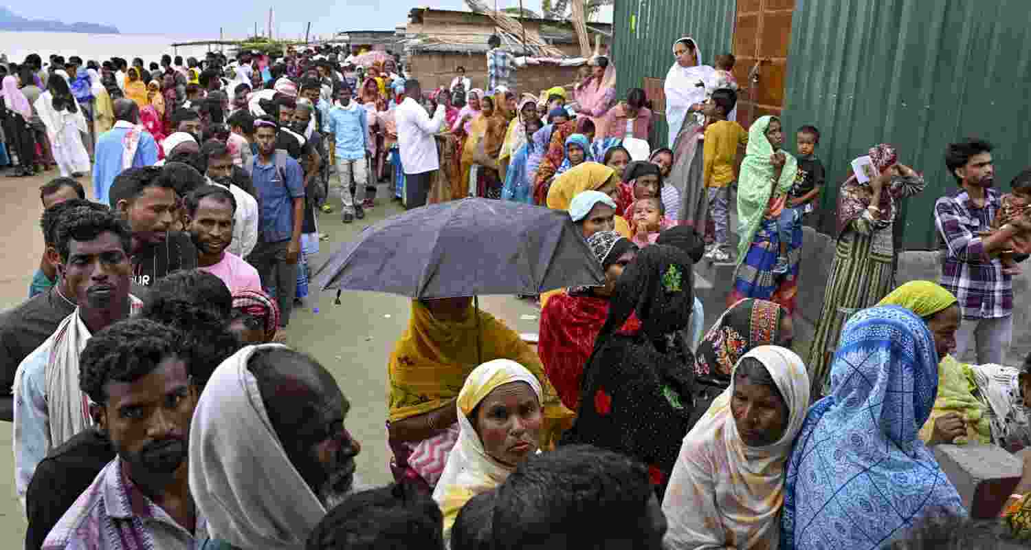 People wait in queues to cast their votes during the Assam Assembly elections, at a polling station, in Darrang district, Assam. 