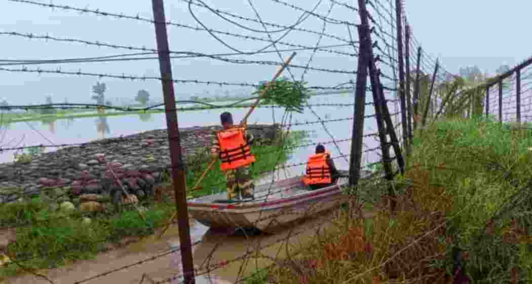 BSF personnel patrolling along the India-Pakistan international border fence on a boat. 