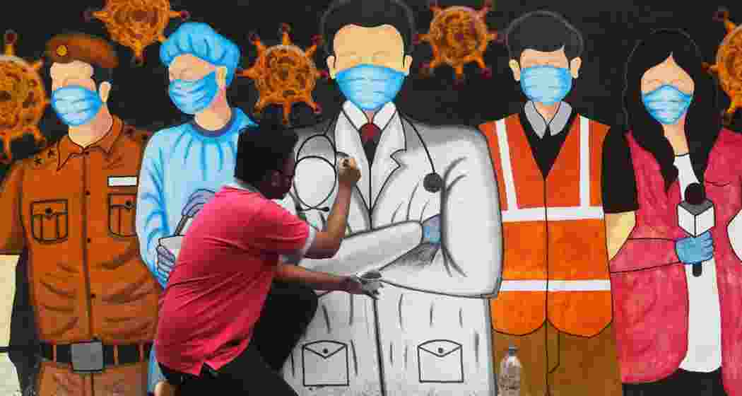 An artist gives finishing touches to a mural depicting frontline COVID workers in Kolkata.