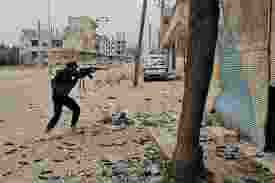 An armed fighter is seen approaching an intersection amid clashes that killed over 200 people in Syria.