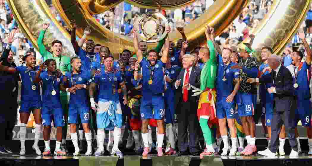 Chelsea players celebrate with the Club World Cup trophy after defeating PSG 3-0 in New Jersey on Sunday, 13 July 2025. President Donald Trump joins them on the podium.