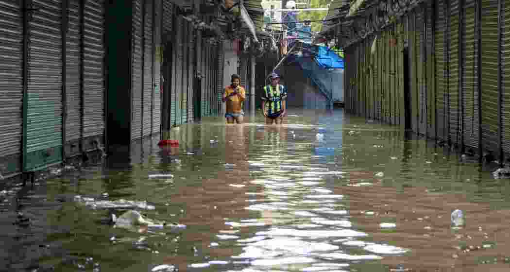 People make their way through a flooded area, near ISBT, in New Delhi.