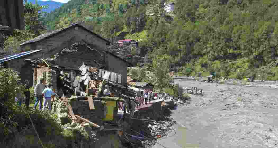 People gather near a house after it was partially washed in the Beas river flowing in spate due to heavy rainfall, in Kullu district, Himachal Pradesh on Wednesday. People gather near a house after it was partially washed in the Beas river flowing in spate due to heavy rainfall, in Kullu district, Himachal Pradesh on Wednesday.