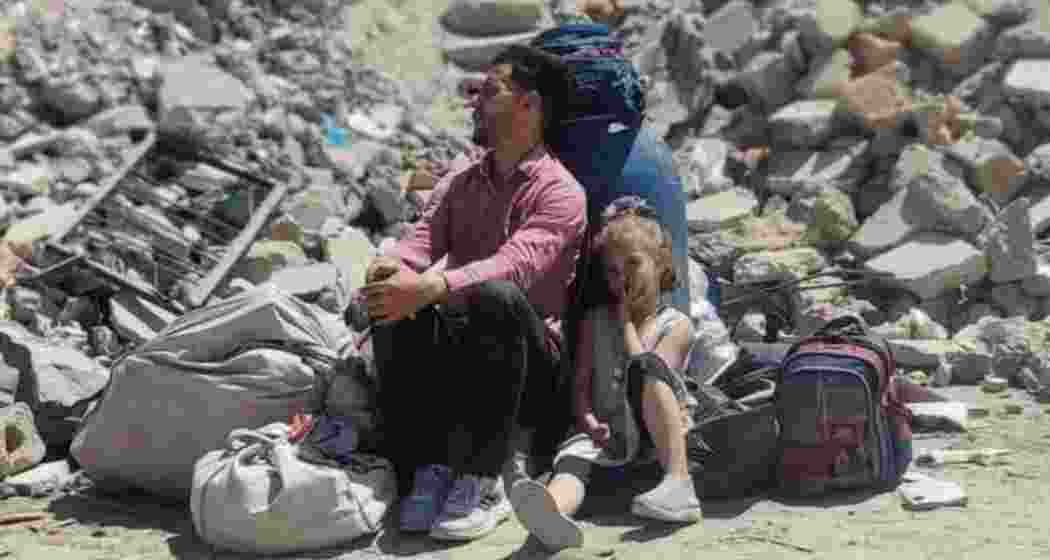 A father and his daughter sit in silence amid the rubble in Gaza, following Israeli air strikes that killed 82 people across the enclave by Saturday dawn.