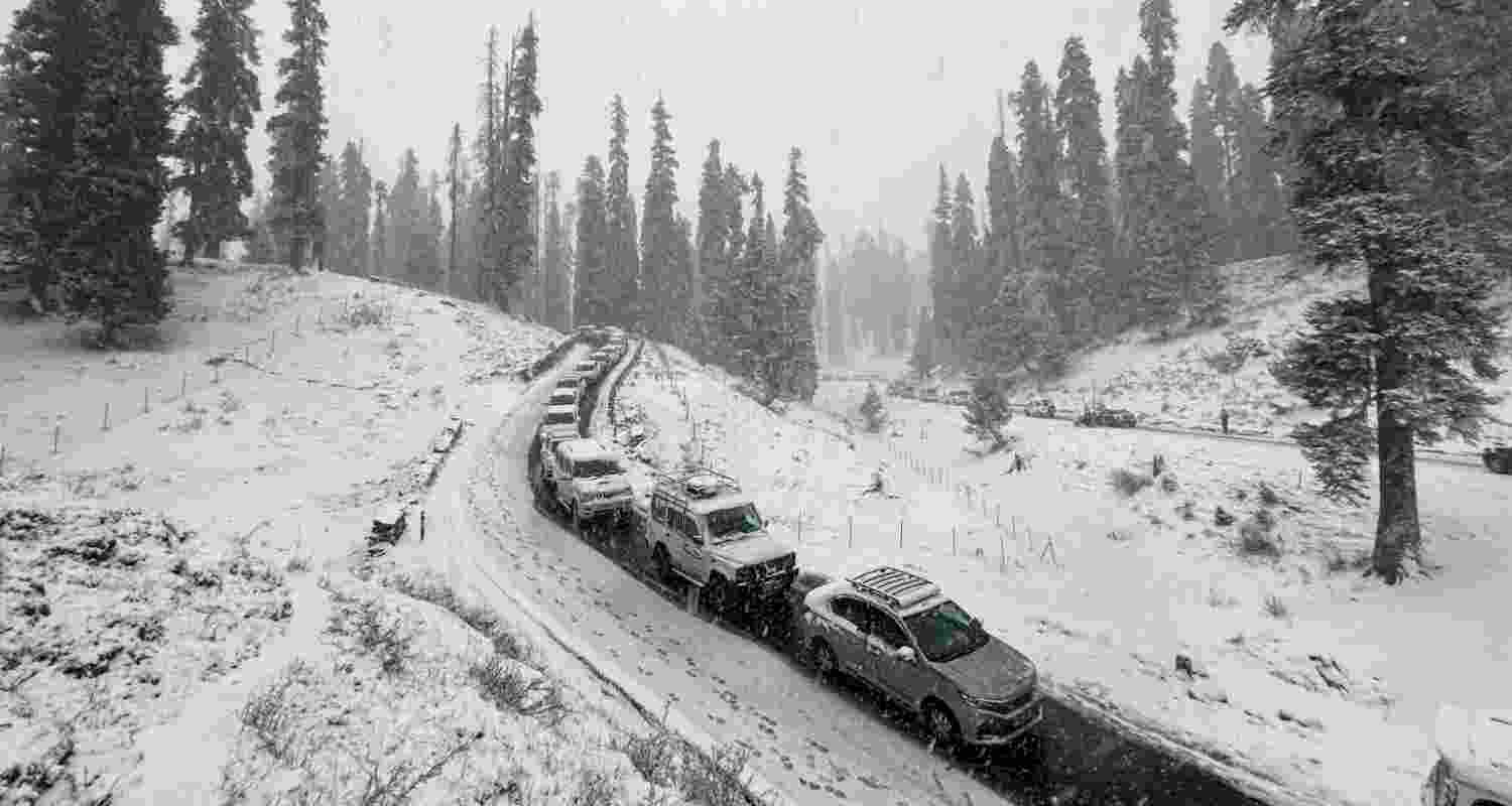 Vehicles move on a road amid light snowfall, in Gulmarg.