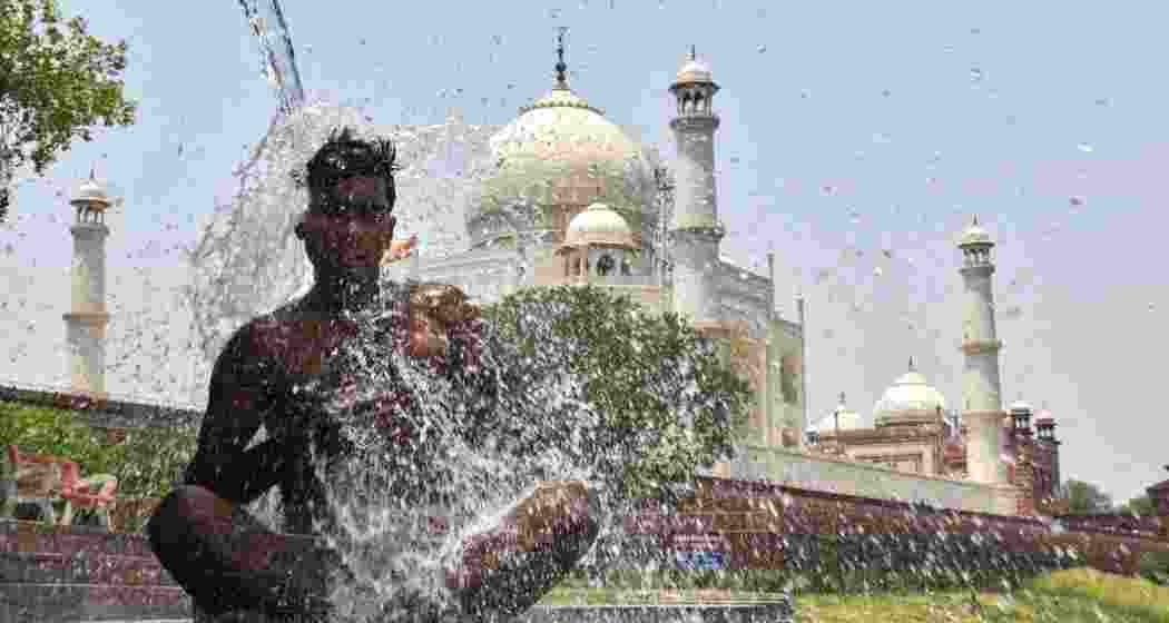 A bathes at the bank of Yamuna river to cool off during a hot summer day, in Agra, Tuesday.