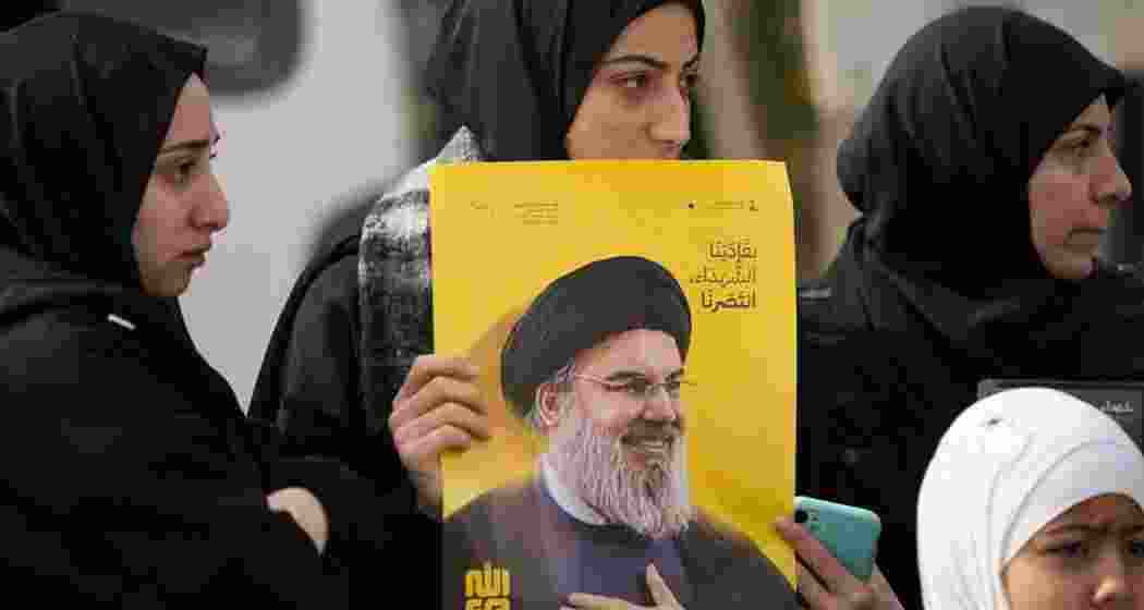 A Lebanese woman holds a portrait of slain Hezbollah leader Sayyed Hassan Nasrallah while waiting with others for permission from the Lebanese army to enter their village, following the Israeli troop withdrawal in Bint Jbeil, southern Lebanon, on 26 January 2025.