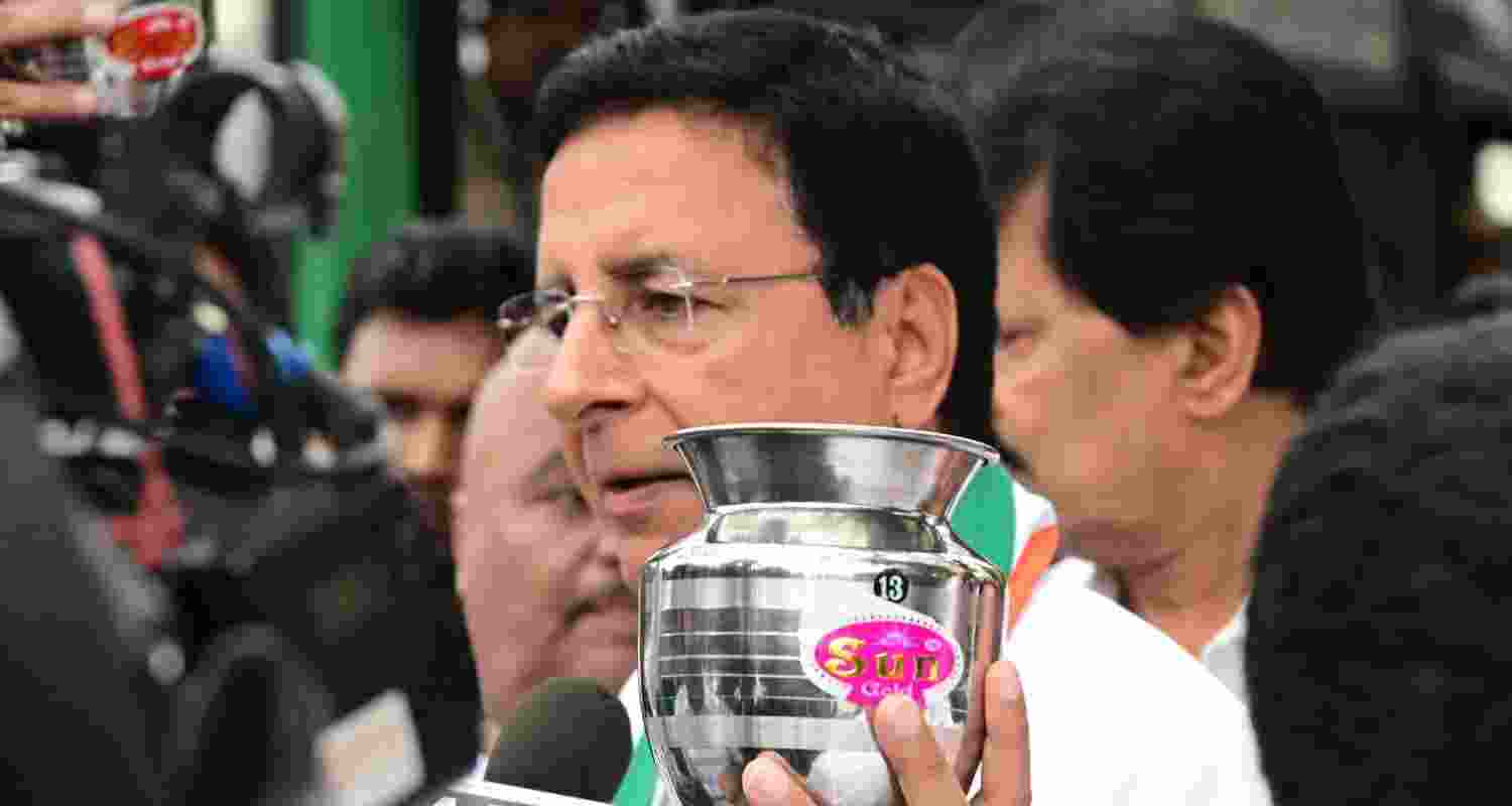 Surjewala in a press breifing comes up with an empty steel vessel showing BJP didn't give anything to Karnataka. Image X. Surjewala in a press breifing comes up with an empty steel vessel showing BJP didn't give anything to Karnataka. Image X.