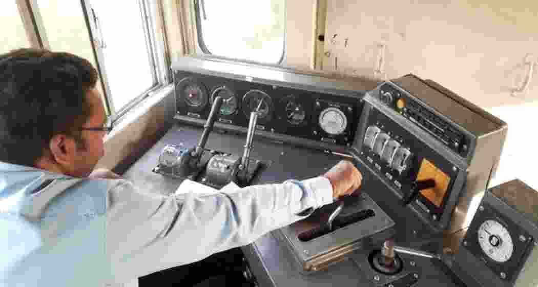 A loco pilot focuses intently while managing the train's dashboard.