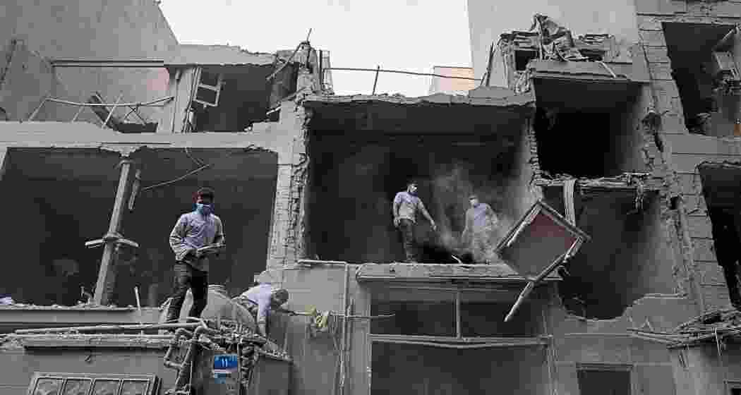 Volunteers clean debris from a residential building damaged when a nearby police station was hit Friday in a U.S.-Israeli strike in Tehran, Iran, on Sunday.