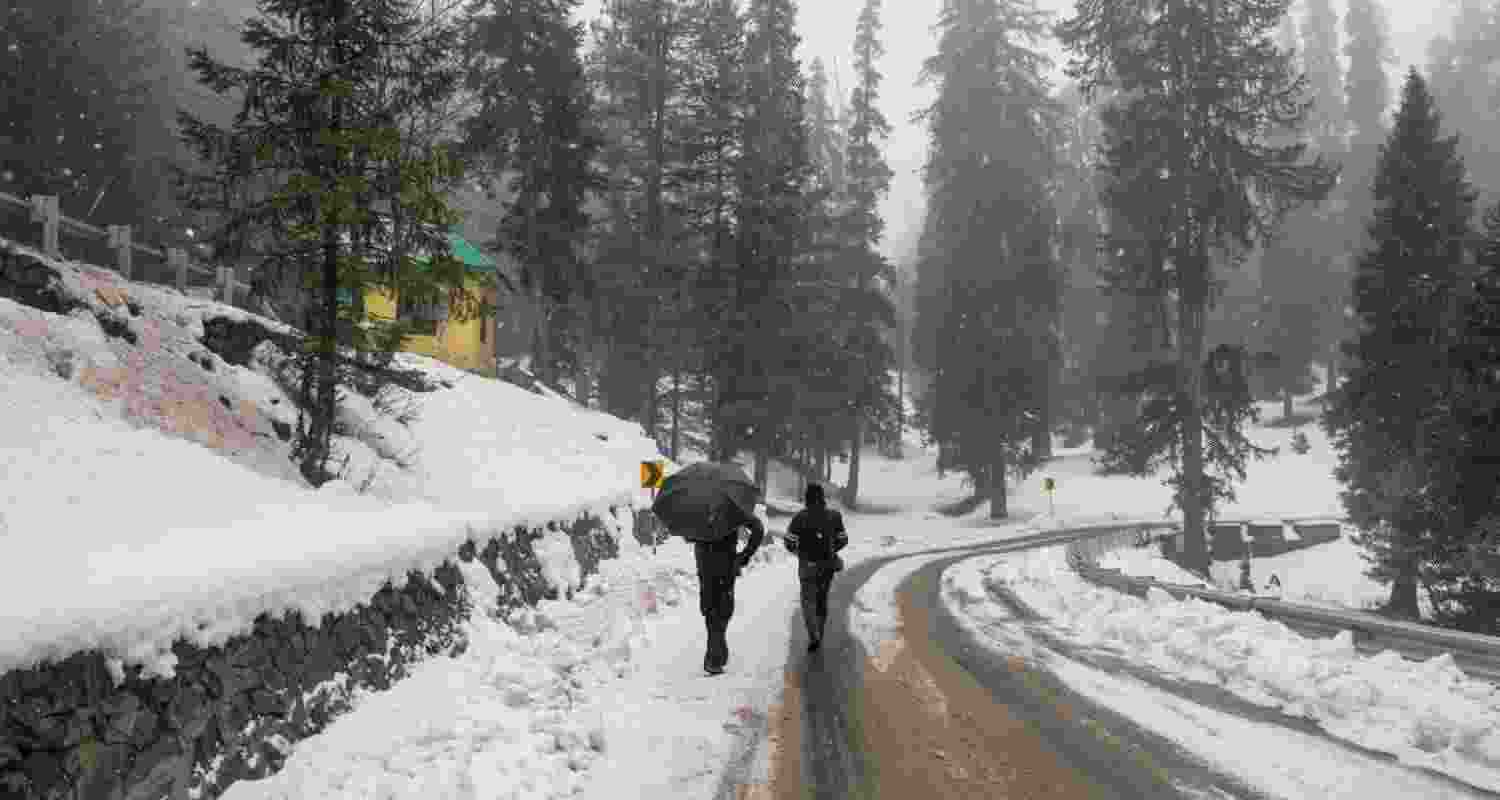 Pedestrians amid snowfall, at Gulmarg in Baramulla district of J&K, Tuesday. 