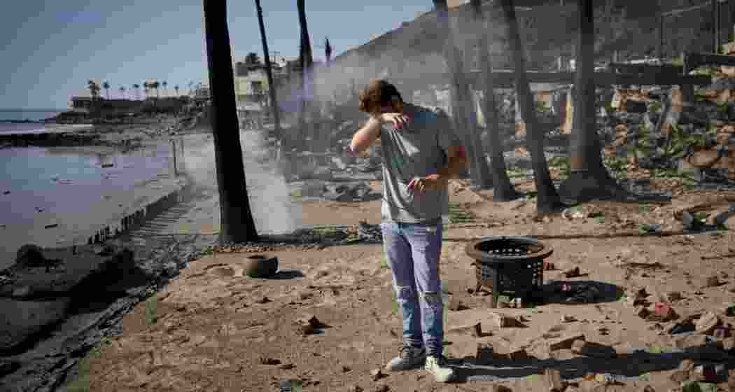 An LA resident reacts as he sifts through the remains of his father's fire-ravaged beach front property in the aftermath of the Palisades Fire Friday, Jan. 10, 2025 in Malibu, Calif. 