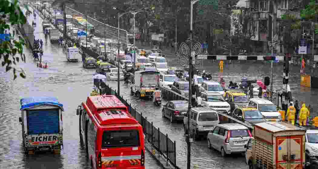 Commuters navigate waterlogged streets in Pune after overnight showers, as IMD issues a heavy rain alert for Pune, Thane, Raigad and Mumbai.