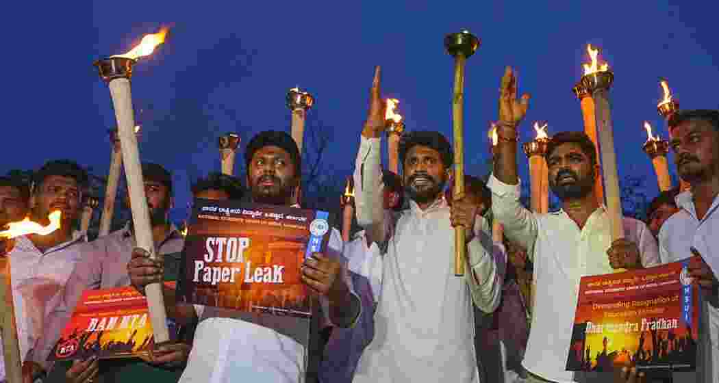 Members of the National Students' Union of India (NSUI) hold torches and placards as they raise slogans during a protest against the against the cancellation of NEET-UG 2026 over a suspected paper leak, demanding the resignation of Union Education Minister Dharmendra Pradhan, at Freedom Park, in Bengaluru, Karnataka, on Thursday. (PTI Photo/Shailendra Bhojak)