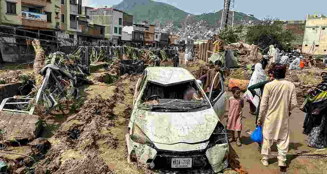 People gather around a damaged vehicle and scattered debris after torrential rain and a massive cloudburst triggered a flash flood in Pakistan’s Khyber Pakhtunkhwa province.