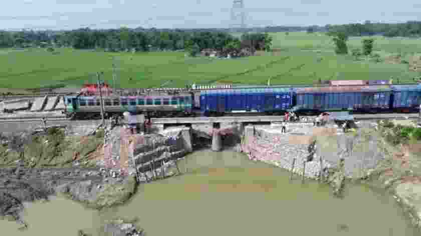A goods train passes over a temporary rail bridge built after the original structure was washed away during the recent floods in North Bengal, as restoration work continues.