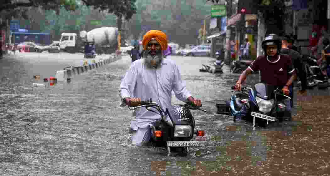 A man on his motorbike wades through a flooded street after heavy rain in New Delhi.