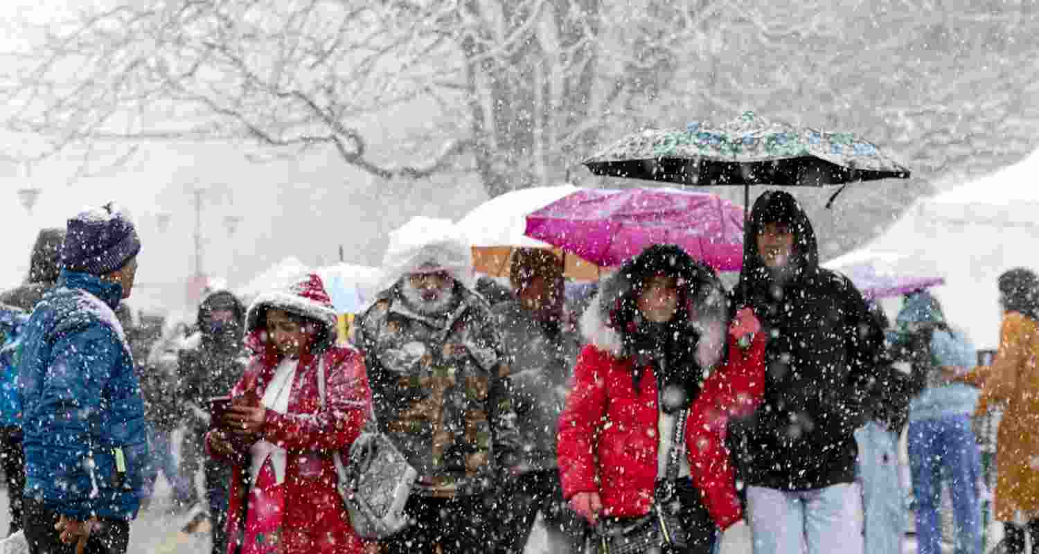 Visitors take a walk amid fresh snowfall, in Shimla, Monday. 