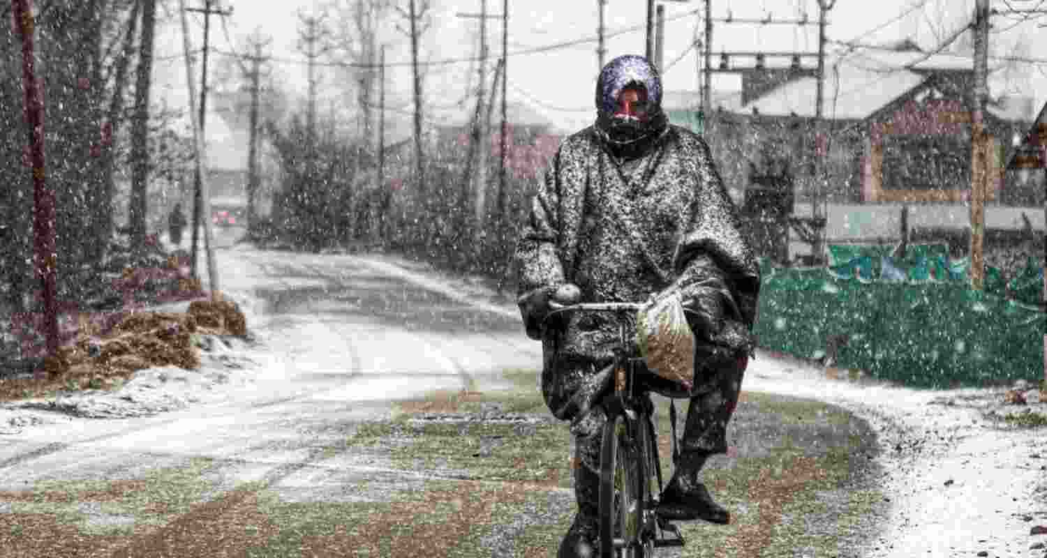  A man rides a bicycle amid snowfall, in Anantnag district, J&K, Thursday. 