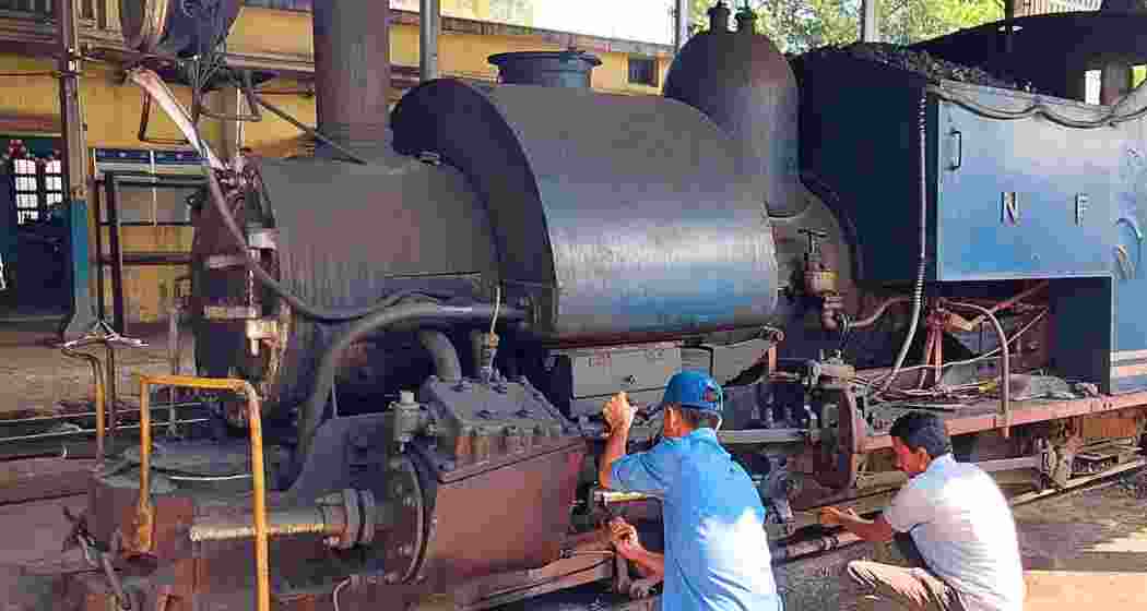 Indian railways personnel repairing a steam engine at the Tindharia Workshop, the historic cradle of the Darjeeling Himalayan Railway, where engines continue to be maintained and restored.
