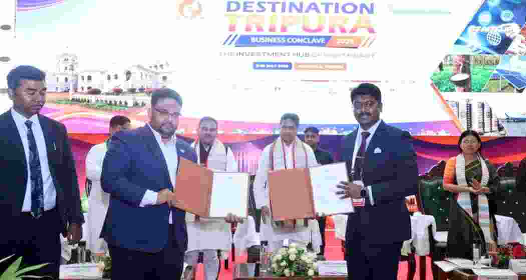 Investors display signed MoU folders during the Destination Tripura Business Conclave 2026 in Agartala as Tripura Chief Minister Manik Saha looks on.