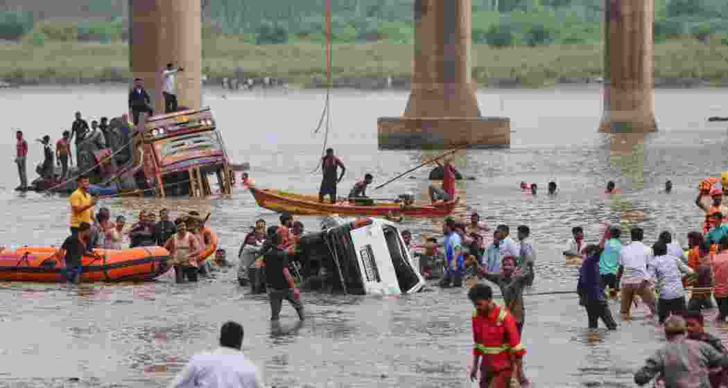 Rescuers and locals look for survivors after several vehicles fell into a river following the collapse of a portion of a bridge in Mujpur near Vadodara in the Indian state of Gujarat, Wednesday.