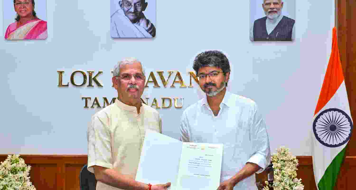 Tamil Nadu Governor Rajendra Vishwanath Arlekar hands over the letter of appointment to TVK chief C Joseph Vijay as the new state Chief Minister, at the Lok Bhavan, in Chennai on Saturday.