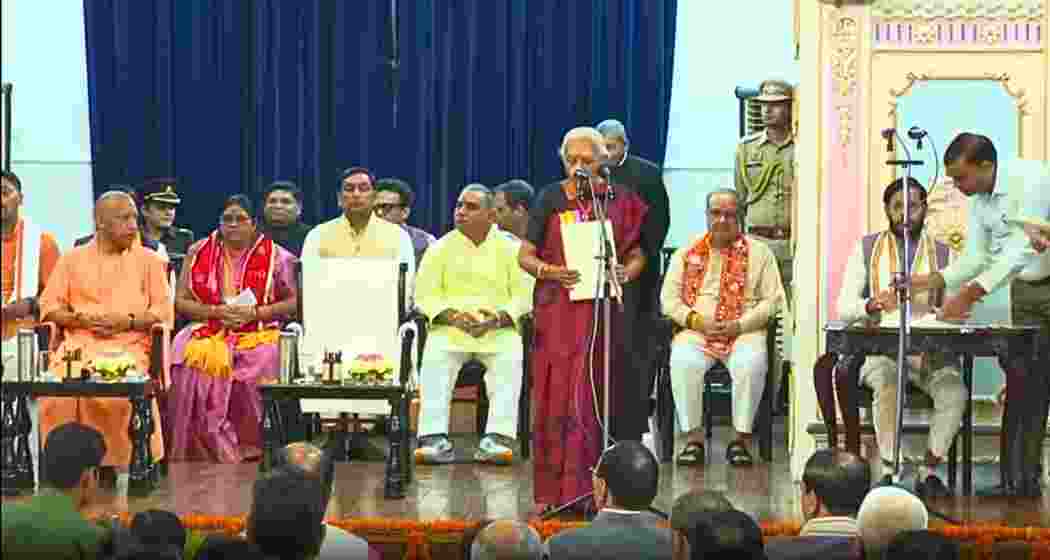Uttar Pradesh Chief Minister Yogi Adityanath (L) looks on as Governor Anandiben Patel administers the oath at Raj Bhavan during the swearing-in ceremony of six BJP leaders inducted into the council of ministers.