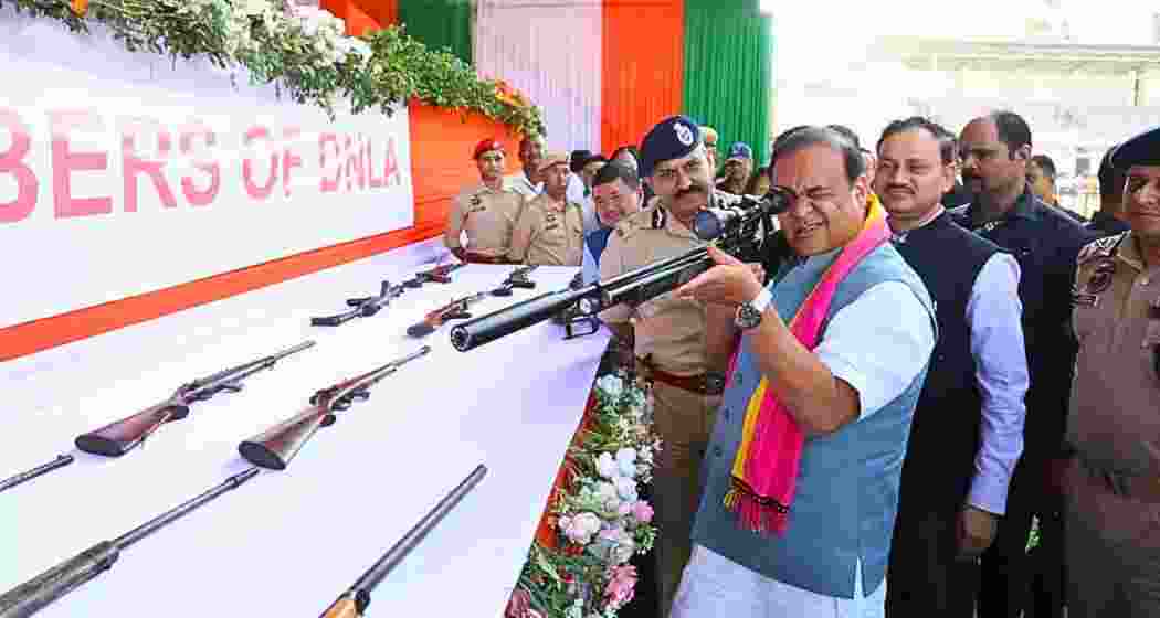 File photo of Himanta Biswa Sarma inspecting a firearm alongside police officials during an official event.