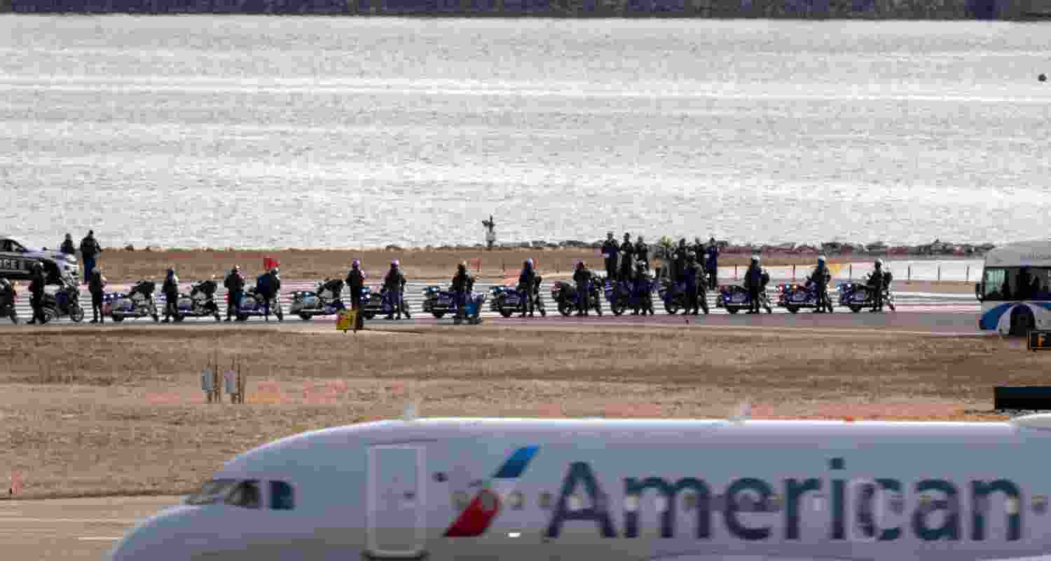 An American Airlines jet passes as police officers escort buses carrying family members of the victims of a mid-air collision between an American Airlines jet and an Army helicopter to runway 33 near the wreckage site in the Potomac River at Ronald Reagan Washington National Airport, Sunday.