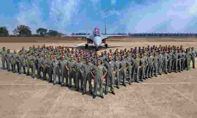 Indian Air Force personnel pose in front of a Rafale fighter jet.