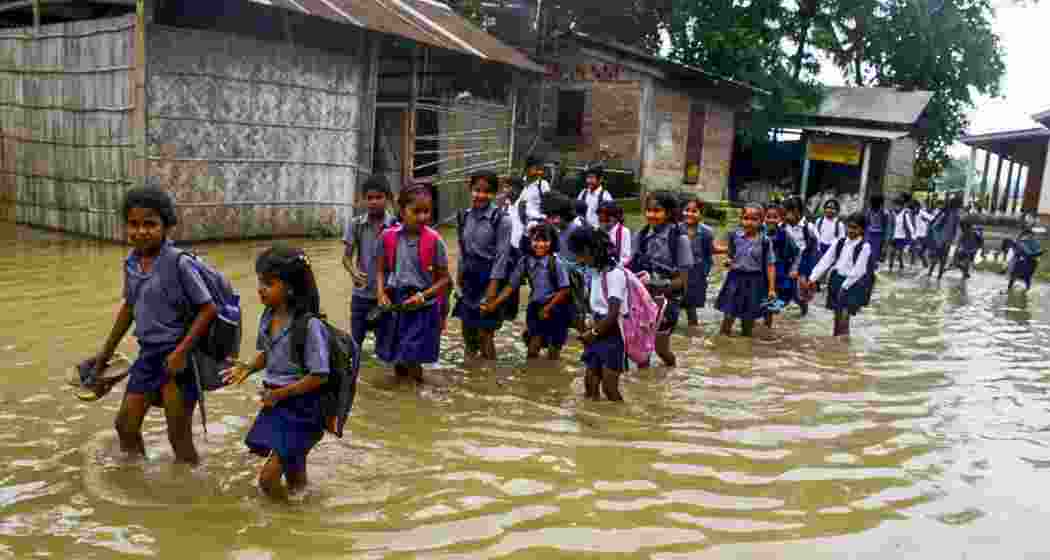  School students wade through floodwaters at Mayang village in Morigaon district of Assam, Tuesday, June 3, 2025.