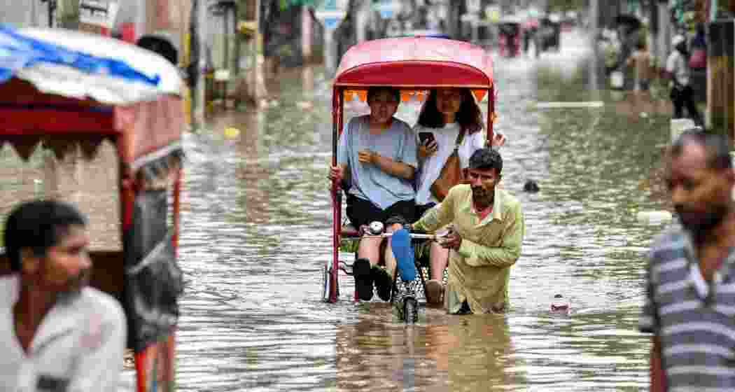 Women ride cycle rickshaws through a waterlogged street in Guwahati on Saturday, after heavy monsoon rain triggered floods and landslides across Assam.