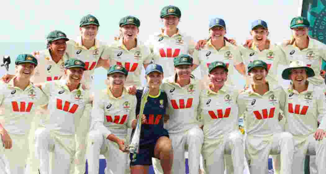 The Australian team celebrate with the trophy at the WACA after their ten‑wicket win over India in the one‑off women’s D/N Test, posing for photographs.