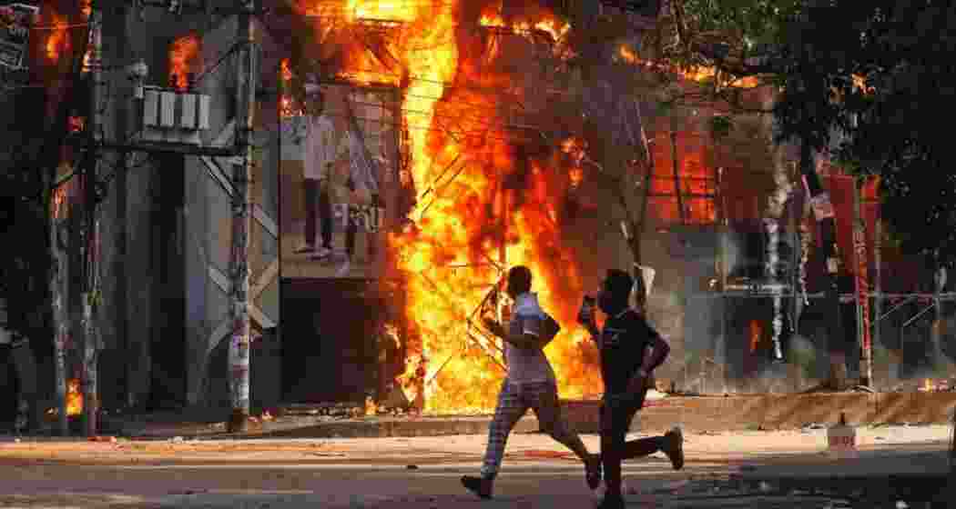Men run past a shopping centre which was set on fire by protesters during a rally against Prime Minister Sheikh Hasina and her government.