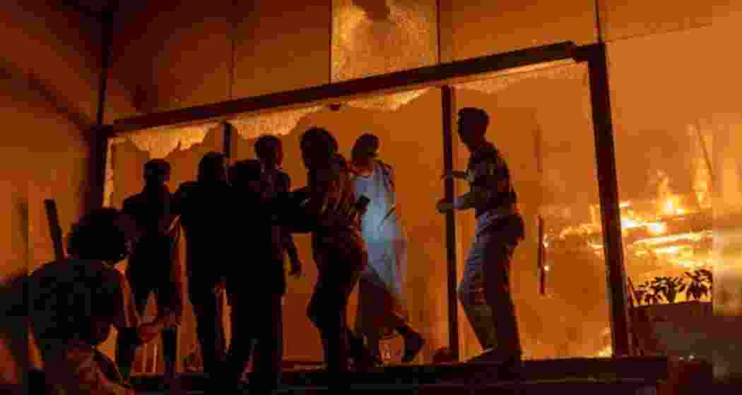 People rush to save themselves from flames at a media house torched by a mob in Bangladesh on Thursday, during protests following the death of Sharif Osman Hadi.