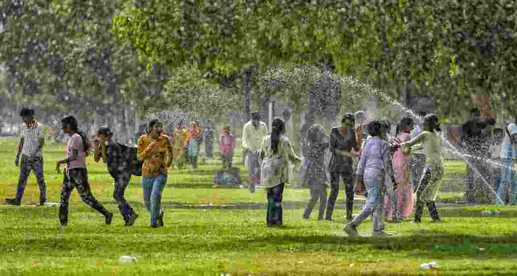 Visitors get drenched as they stand near sprinklers for respite from the scorching heat, at the lawns near Kartavya Path in New Delhi, Monday. Visitors get drenched as they stand near sprinklers for respite from the scorching heat, at the lawns near Kartavya Path in New Delhi, Monday.