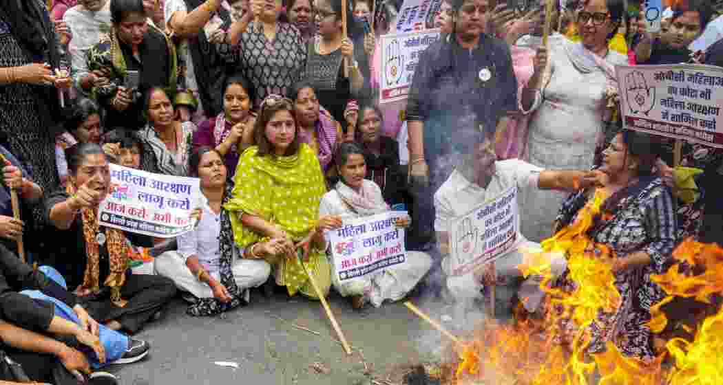 Congress workers burn an effigy during a protest march towards the BJP headquarters over the Constitution (131st Amendment) Bill on women's reservation, in New Delhi, on Sunday.