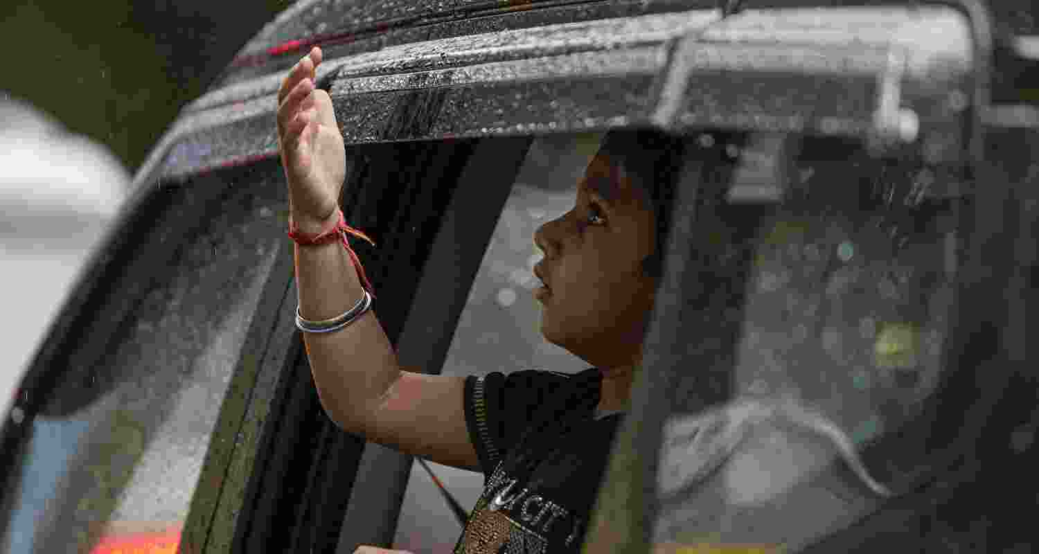 A child peeks out of a car window amid rainfall, in New Delhi, Tuesday, April 7, 2026.