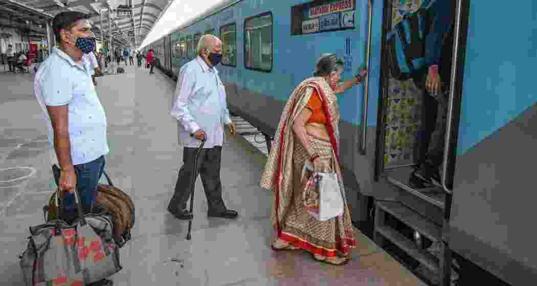 An elderly couple boards a train. 