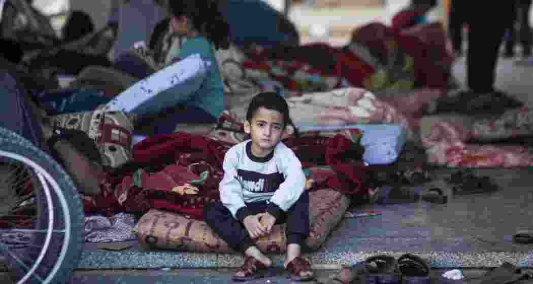 A Palestinian child sits beside the rubble of a destroyed school building in Gaza, where many children like him had taken shelter before it was reduced to ruins by Israeli strikes.