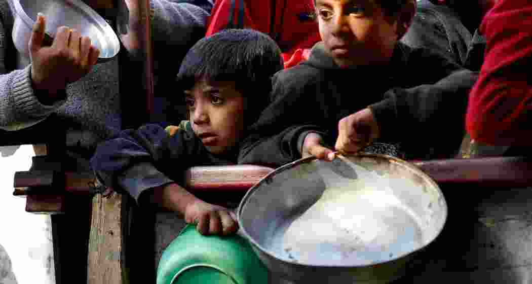 Palestinians wait to receive food cooked by a charity kitchen in Gaza's Rafah amid shortages of food supplies.