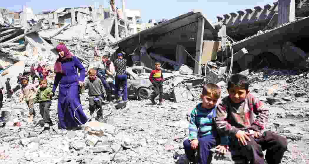 Children look on as people walk amid the rubble of a building destroyed in an overnight Israeli strike in the northern Gaza Strip. (File photo).