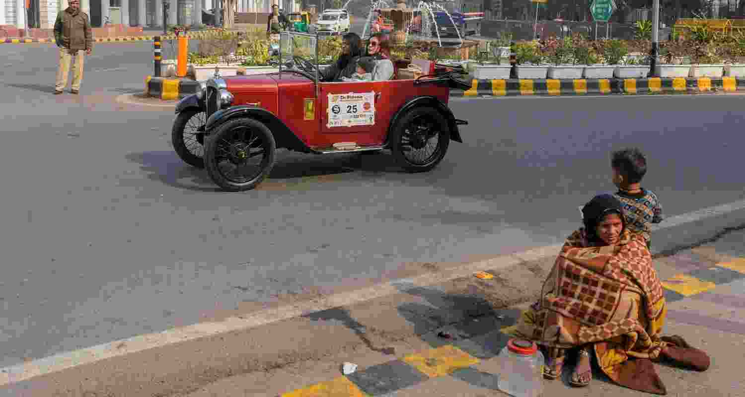 Two worlds apart: Two women ride their vintage car, while a homeless woman sits at the curb with a child, at the 57th edition of the Statesman Vintage & Classic Car Rally, at Connaught Place, in New Delhi. Two worlds apart: Two women ride their vintage car, while a homeless woman sits at the curb with a child, at the 57th edition of the Statesman Vintage & Classic Car Rally, at Connaught Place, in New Delhi.