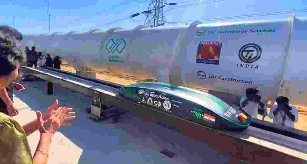 A replica of the Hyperloop demonstrates its working mechanism, with the IIT Madras Hyperloop tube in the background, as Union Minister Ashwini Vaishnaw, scholars, and professors witness the event.
