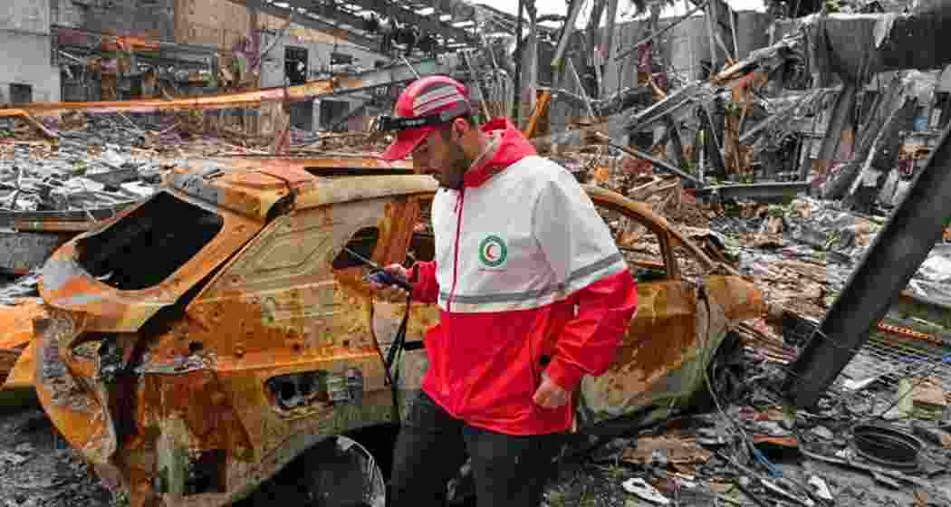 A member of the Iranian Red Crescent Society walks at Hypercar, an auto service center, amid damages which according to the company's officials was caused by strikes.
