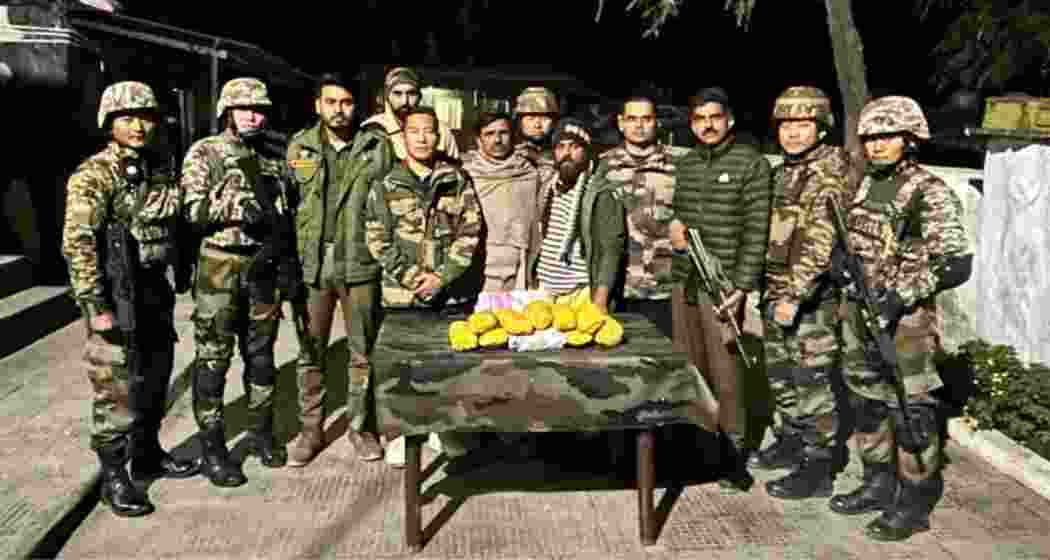 Security forces with the heroin seized from the two smugglers (in the middle) arrested in Rajouri, Jammu and Kashmir, as part of a joint operation to thwart a cross-border drug smuggling attempt.