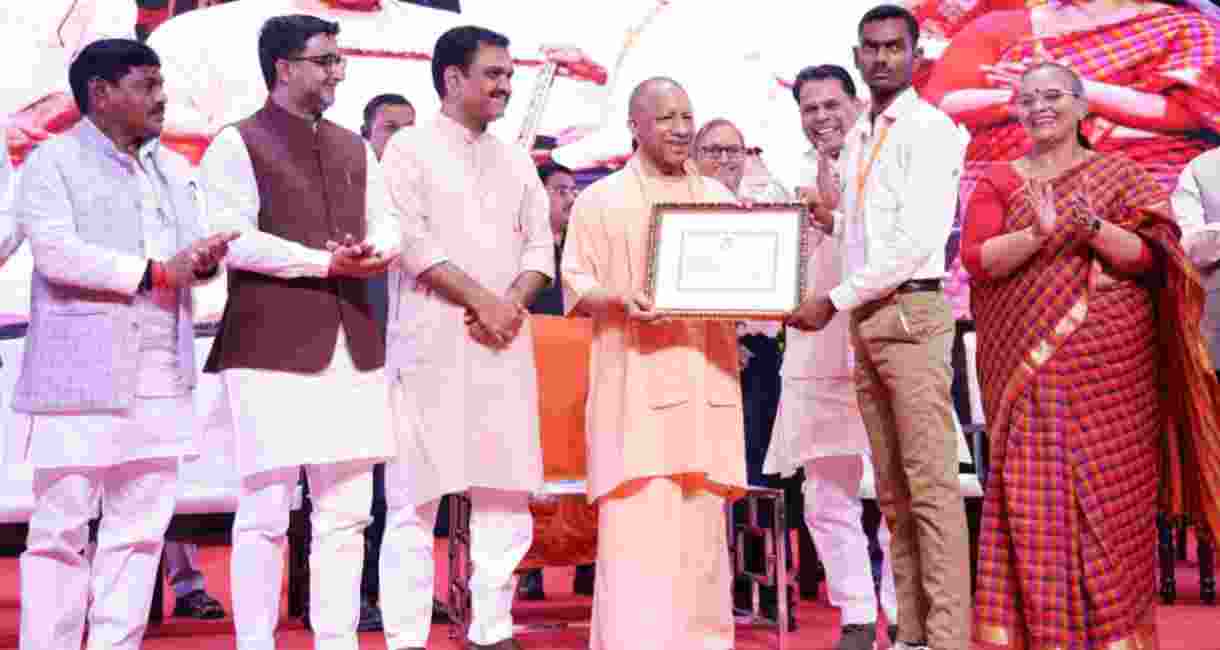 Uttar Pradesh Chief Minister Yogi Adityanath distributes scholarship to students at a scholarship distribution programme in Lucknow.